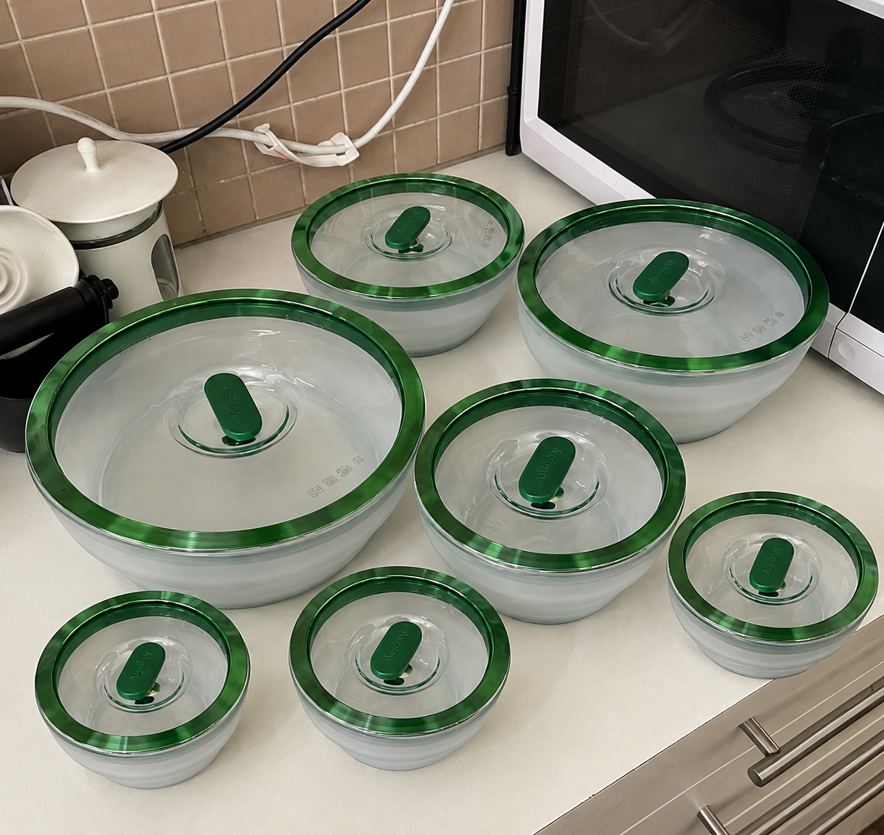 Kit de 7 potes de vidro com tampa verde na bancada da cozinha